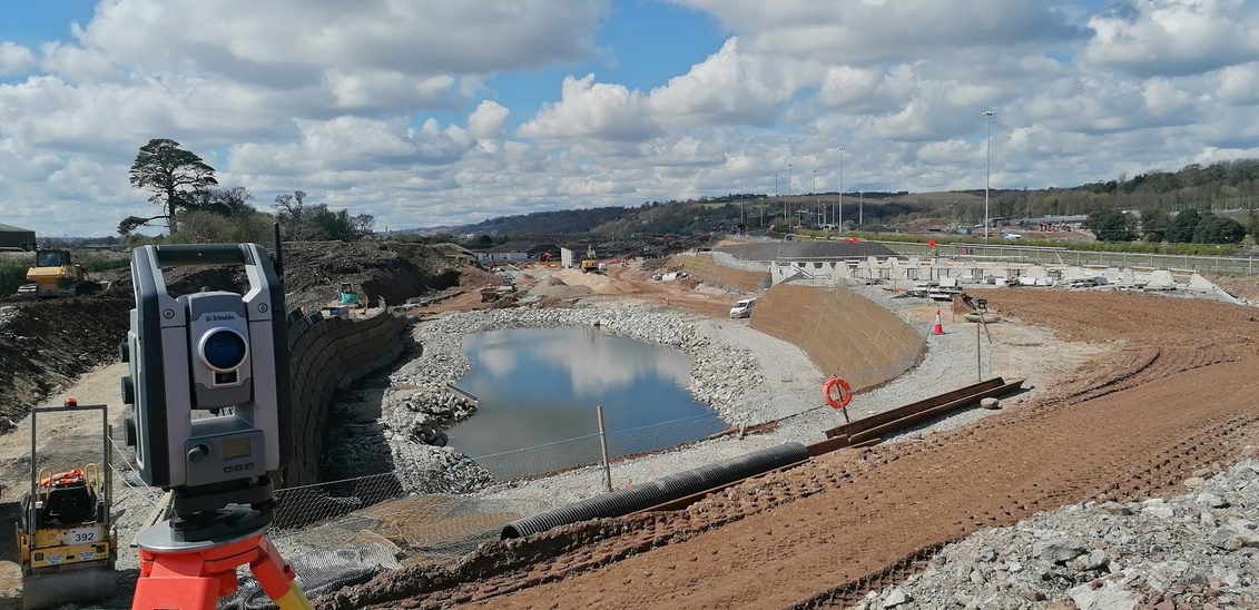 Total station overlooking earthworks and attenuation pond at Dunkettle Interchange