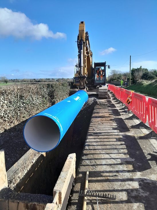 Large diameter blue watermain pipe being lowered into a trench in Waterford